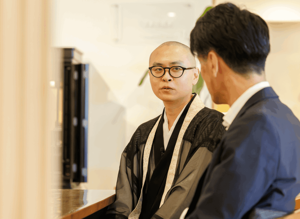 僧侶と男性が打ち合わせをしている様子
